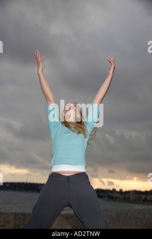 Femme en tendant les bras en avant des nuages sombres, low angle view Banque D'Images