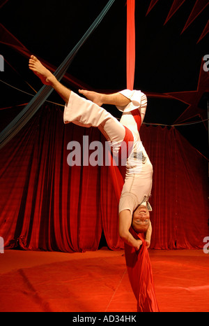 Artiste de cirque acrobat enchevêtré dans rideaux rouge Banque D'Images