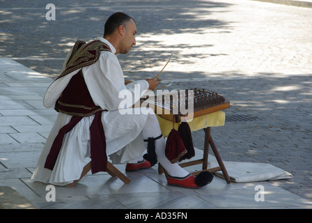 Athènes homme de bus et de jouer des instruments de musique assis sur le trottoir à l'ombre lors d'une chaude journée d'été dans la zone touristique Grèce Banque D'Images