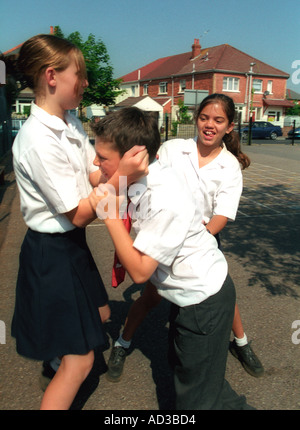 Les filles brime un jeune garçon à l'école. posés par les modèles Banque D'Images