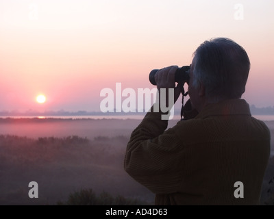 East Mersea Essex tôt le matin aube brume silhouette retraité marcheur jumelles oiseau observation de boue plats basse marée Rver Colne Mersea Island Angleterre Royaume-Uni Banque D'Images