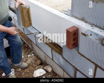 Essex House emplacement près de charpentier à l'aide d'une truelle pour jeter la lumière blocs isolants Celcon poids en mur creux 3xyz Banque D'Images