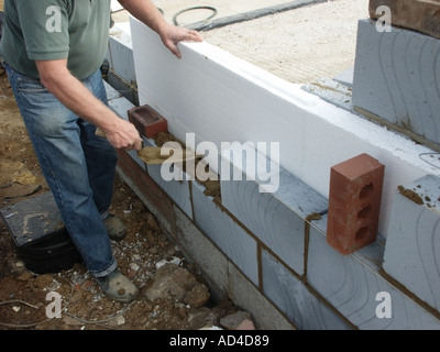 Charpentier pose blocs Celcon sur lit de mortier à la ligne de chaîne pour mur creux avec isolant en polystyrène pour l'efficacité énergétique des Angleterre UK Banque D'Images