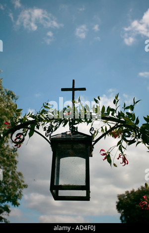 Croix en fer forgé noir et lampe au-dessus de la porte menant à la 12e siècle, église St Michaels Amberley Village, Sussex, UK Banque D'Images