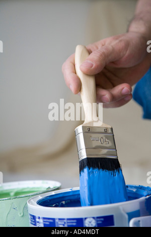 Personne trempant un pinceau dans une boîte de peinture Banque D'Images