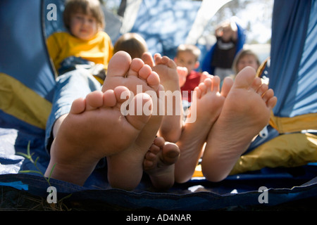 Vue sur les pieds des enfants poussant hors de la tente Banque D'Images