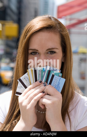 Une adolescente) tenant un fan de cartes de crédit sur sa bouche Banque D'Images