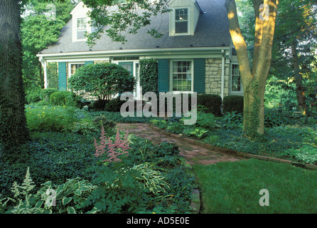 Maison en pierre de style Cape Cod et voie de brique entouré d'arbres dans un jardin ombragé Midwest USA Banque D'Images