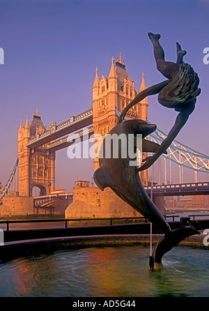 TOWER BRIDGE misty sunrise Girl et statue de dauphin au lever du soleil avec le Tower Bridge derrière Londres UK Banque D'Images