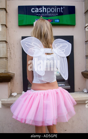 Jeune femme slim habillé en tutu et des ailes comme une fée obtenir de l'argent d'ATM à Aberystwyth, Ceredigion West Wales Banque D'Images