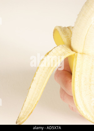 La main avec la moitié de la banane pelées Banque D'Images