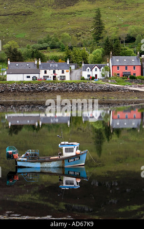 Maisons peintes de couleur pêche et voile reflétée dans l'eau à côté du château Eilean Donan en Ecosse Banque D'Images