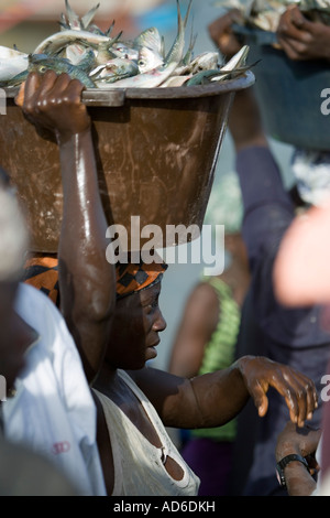 Les jeunes femmes portent des bassins de poissons frais sur la tête de plage sur le marché aussi ouvrir les bateaux de pêche arrivent avec la Gambie Tanji capture Banque D'Images