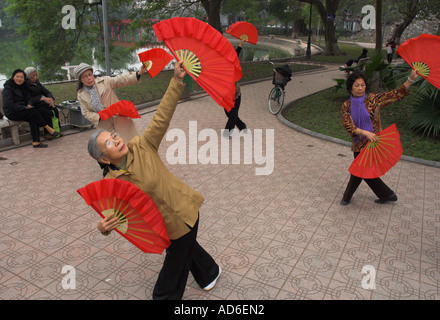 Lac Hoan Kiem Hanoi Vietnam femmes âgées, la mise en œuvre d'exercices traditionnels matin femmes danse avec main rouge fans Banque D'Images