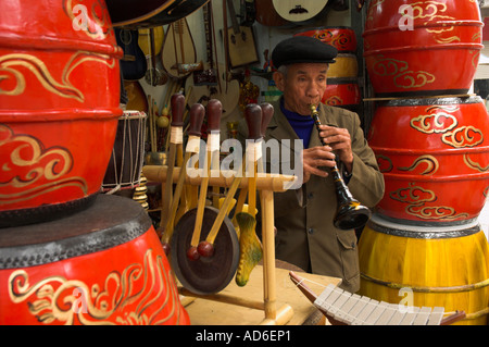 Vietnam Hanoi la vieille homme âgé dans magasin de musique jouant sur une flûte traditionnelle Banque D'Images