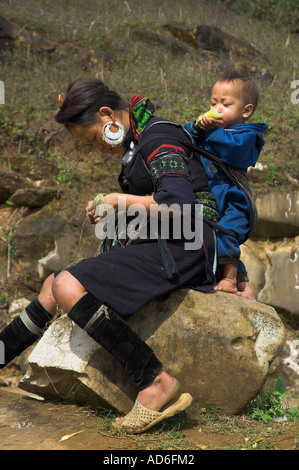 Les minorités ethniques du Vietnam Sapa jeune femme vêtu du costume traditionnel avec bébé au dos assis et rock ona Banque D'Images