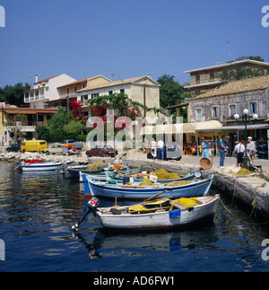 Des bateaux de pêche amarrés au quai avec taverna boutique et maisons sur harbourside Kassiopi Corfou les îles Grecques Banque D'Images