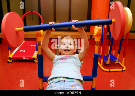 4 ans, fille d'un centre de loisirs, à l'aide de poids en creche, Brixton, London, UK. Banque D'Images