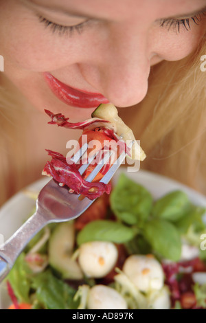 Young blonde woman eating salad, smiling Banque D'Images