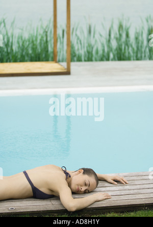 Femme couchée sur le pont près de la piscine, le lac en arrière-plan Banque D'Images