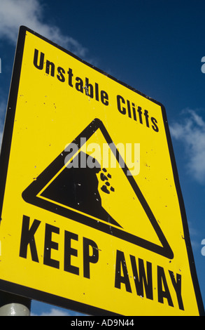 Close up de panneau jaune contre un ciel bleu profond et montrant la chute de rochers avec des mots tenir loin des falaises instables Banque D'Images