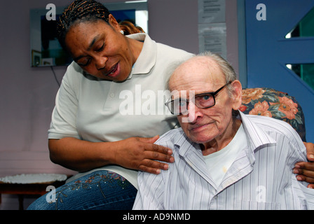 Membre du personnel de soin de la femme avec un homme âgé au foyer de soins pour personnes atteintes de démence, Londres, Royaume-Uni. Banque D'Images
