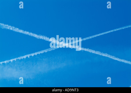 Des traînées de vapeur en forme de croix dans un ciel bleu Banque D'Images