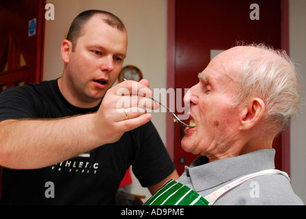 Membre du personnel aidant soins homme âgé avec l'alimentation en foyer de soins pour personnes atteintes de démence, Londres, Royaume-Uni. Banque D'Images