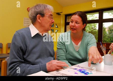 Membre du personnel de soins avec un homme âgé dans la classe d'art au foyer de soins pour personnes atteintes de démence, Londres, Royaume-Uni. Banque D'Images