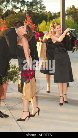 Une demoiselle d'arrivée reçoit un baiser d'une groomsman comme elle et les autres demoiselles d'arriver pour un mariage catholique dans Lag Banque D'Images