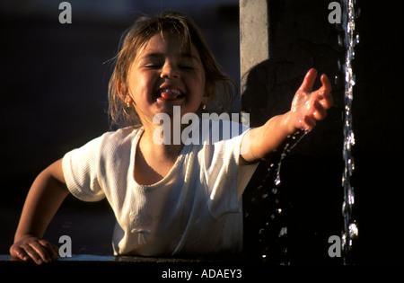 Fille jouant avec de l'eau à une fontaine Banque D'Images