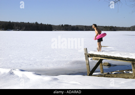 Homme avec tube intérieur prêt à nager à regarder lac gelé Banque D'Images
