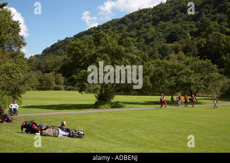 Les touristes allongés sur l'herbe et d'autres marchant le long chemin sous les collines sur un terrain découvert en raison de monastique glenalough Banque D'Images