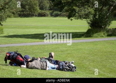 Les touristes allongés sur l'herbe au soleil avec des sacs ouverts en raison de glenalough site monastique Banque D'Images