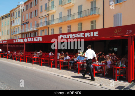 Le Senequier Patisserie et le bar-restaurant transportant des boissons en marchant le long du front de mer servant des clients assis à l'ombre à St Tropez Sud de la France Banque D'Images