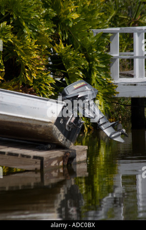 L'extrémité arrière du petit bateau de pêche avec moteur échoué sur un quai en bois Banque D'Images