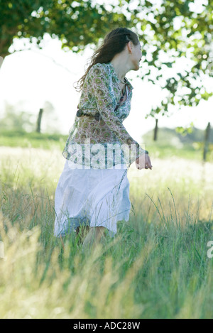 Young woman standing in field, looking over shoulder Banque D'Images