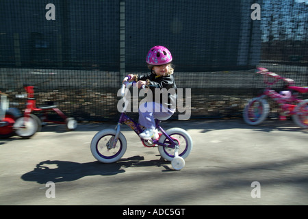 Petit bébé fille équitation vélo avec roues de formation et le casque Banque D'Images