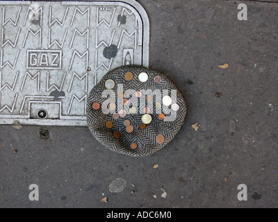 Un des amuseurs de tweed cap se trouve sur un trottoir couvert de pièces Banque D'Images