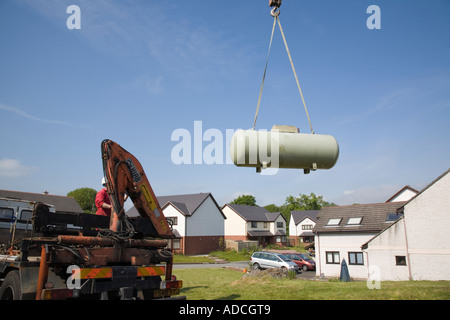 Grand réservoir de gaz d'être hissé Calor par une grue d'un jardin pour un camion contre le ciel bleu. Royaume-uni Grande-Bretagne Banque D'Images