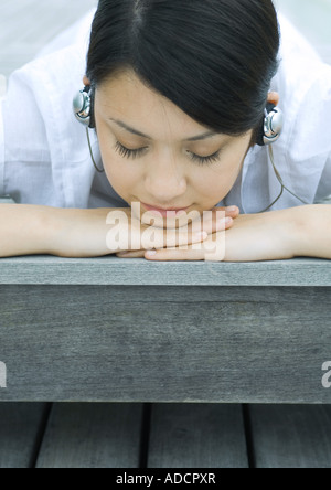 Femme couchée sur lame de listening to headphones Banque D'Images