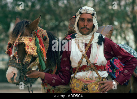 Horseman en vêtements traditionnels en tenant son cheval qui a l'oeil défenseurs contre le soleil et la poussière Banque D'Images