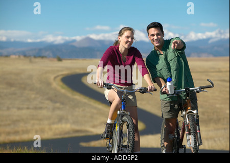 Smiling couple d'âge moyen faire du vélo sur un sentier de montagne dans l'backgroundman horizontal points Banque D'Images