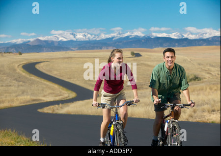 Couple d'âge moyen faire du vélo sur un sentier de montagne dans l'arrière-plan Banque D'Images