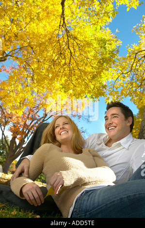 30 ans couple est assis sous les arbres d'Automne doré Banque D'Images