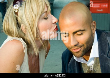 Young blonde woman kissing un homme noir sur le front Banque D'Images