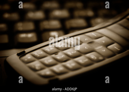 Closeup détail d'un téléphone cellulaire numérique et un clavier d'ordinateur portable Banque D'Images