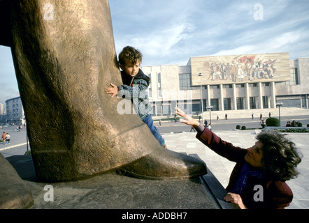 L'Albanie femme raconte son fils à embrasser la jambe de la statue d'Enver Hoxha fondateur de l'état communiste après LA SECONDE GUERRE MONDIALE en Albanie Banque D'Images