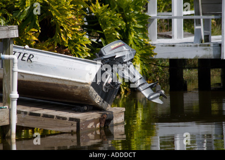 L'extrémité arrière du petit bateau de pêche avec moteur échoué sur un quai en bois Banque D'Images