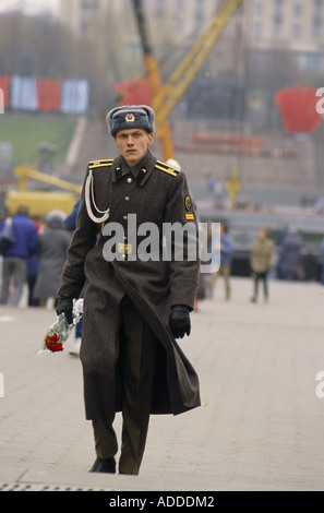 Un soldat en uniforme militaire soviétique porte des roses rouges le jour de la Révolution, le 7th novembre 1989, dans le centre de Kiev, en Ukraine Banque D'Images